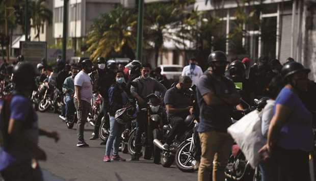 Bikers wait in a queue to refuel their tanks at a gas station, in Caracas yesterday amid the coronavirus outbreak. Venezuela has increased fuel prices, putting a limit on state  subsidies that for decades had allowed citizens to fill their gas tanks virtually for free.