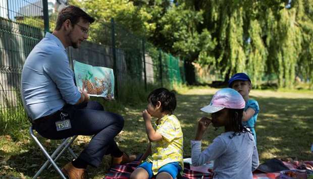 A teacher reads children a story in the grounds of St Dunstanu2019s College junior school as some schools reopened following the outbreak of the coronavirus in London, Britain, yesterday.
