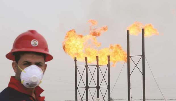 Flames emerge from flare stacks at Nahr Bin Umar oilfield, as a worker wears a protective mask, following an outbreak of coronavirus, north of Basra, Iraq (file). In May, Iraq sold 99.5mn barrels of crude oil at an average price of $21, earning $2.09bn for the month.