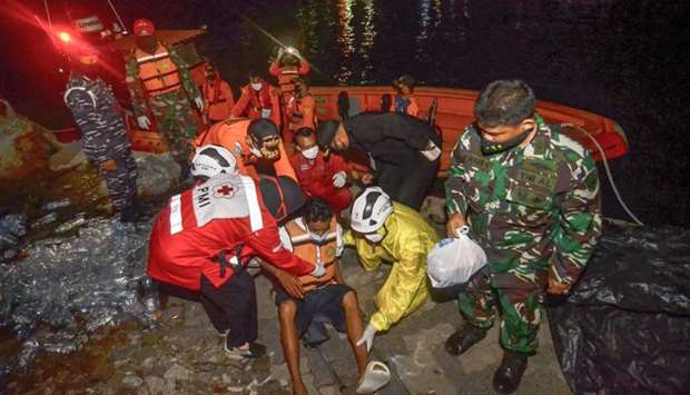 Rescue team members evacuate one of six survivors of a capsized passenger boat carrying 16 people in the Sunda strait near Anak Krakatau in Merak, Indonesia's Banten province
