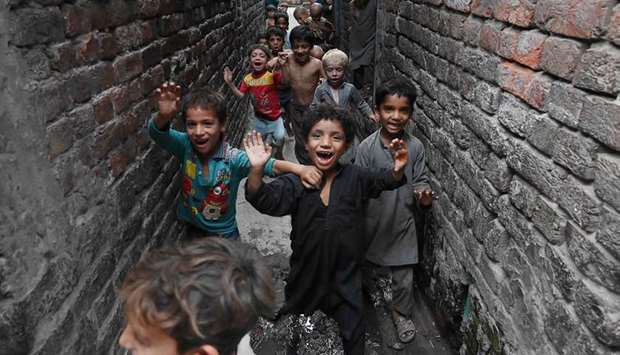 Children of Afghan refugees at a Lahore slum wave to the photographer.