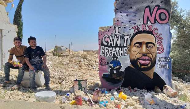 Artists Aziz Asmr and Anis Hamdoun pose next to a graffiti of George Floyd in Idlib, Syria, yesterday.