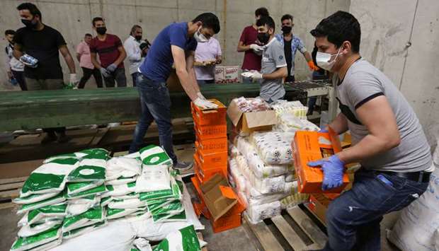 Volunteers wearing protective masks and gloves sort boxes with food for distribution to people in need, in Beirut, Lebanon.