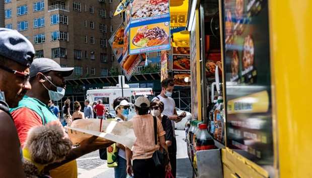 People wearing protective face masks get food from a street vendor near Central Park, in the Manhattan borough of New York City