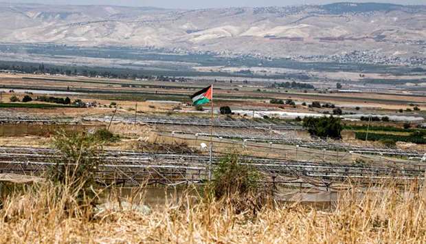 A Palestinian flag is seen in the village of Bardala in the Jordan Valley in the occupied West Bank, with Jordanian villages east of the Jordan river seen in the background.