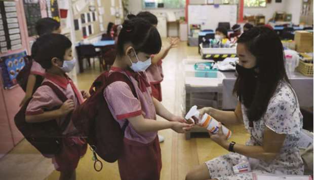 Children wearing protective face masks sanitise their hands as they attend preschool classes at St Jamesu2019 Church Kindergarten as schools reopen amid the coronavirus disease outbreak in Singapore yesterday.