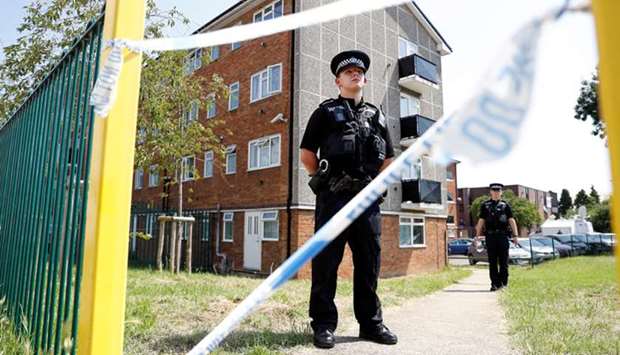 Police officers guard the block where the suspect of multiple stabbings allegedly lived, in Reading, Britain, yesterday.