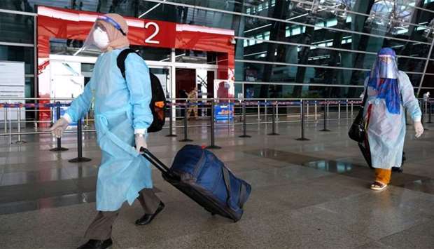 Travellers wearing PPE walk through the Indira Gandhi International Airport in New Delhi, India