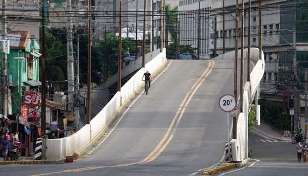 A resident riding a bicycle passes through an empty road in Cebu City, central Philippines yesterday.