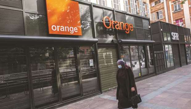 A woman wearing a protective face mask passes shuttered Orange and SFR mobile phone stores during coronavirus lockdown in Toulouse. Orange will soon put a new payments partner in place for its Orange Bank unit, according to a source. While its issues with Wirecard are mostly technological, the debacle at the company is accelerating a change to a new provider, the source said.