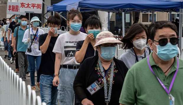People wearing face masks gather at an outdoor area during a mass testing for the coronavirus at the Jinrong Street testing site in Beijing yesterday.