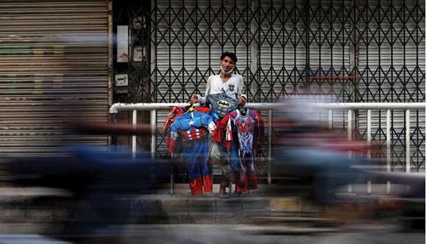 A man selling superhero costumes for children stands by the roadside in Karachi after markets are closed in an effort to stop the spread of the coronavirus.