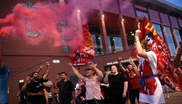 Fans celebrate Liverpool winning the championship title of the English Premier League following Chelsea's 2-1 victory over Manchester City, outside Anfield stadium in Liverpool, north west England