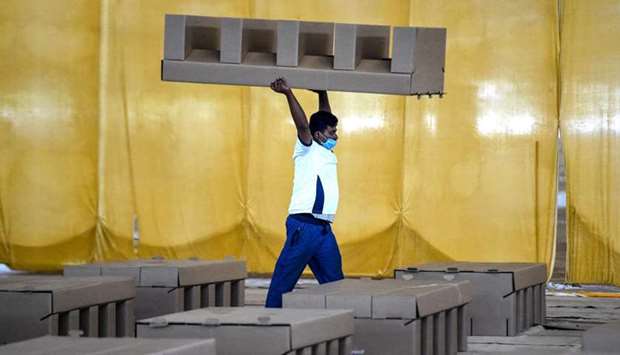 a worker carrying a cardboard bed inside the campus hall of spiritual organisation Radha Soami Satsang Beas (RSSB) which is being converted into a 10,000 beds coronavirus care centre in New Delhi.