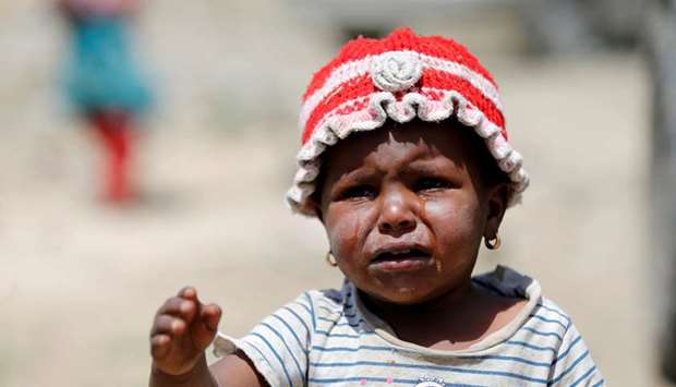 File photo shows a girl crying as she waits with relatives to receive food aid from the local charity, Mona Relief, on the outskirts of Sanaa, Yemen.