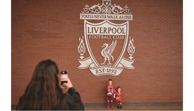 Two young Liverpool fans have their photographs taken beneath the club crest as supporters celebrate winning their first Premier League title in 30 years outside Anfield stadium in Liverpool yesterday. (AFP)