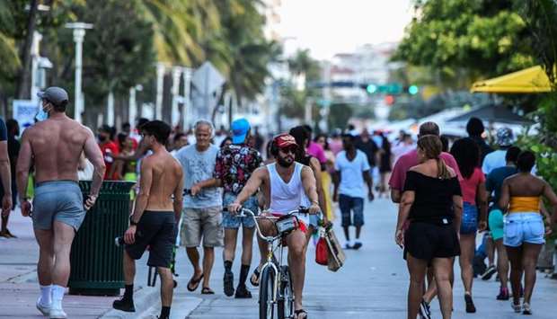 A man rides a bicycle as people walk on Ocean Drive in Miami Beach, Florida. AFP