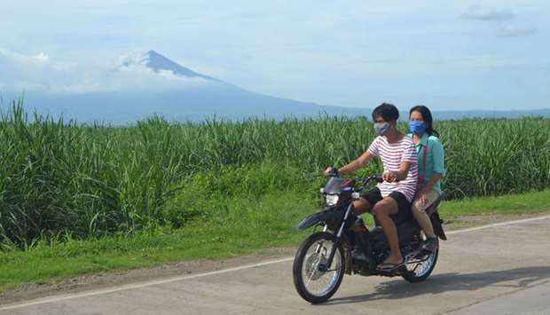 A motorcyclist rides along a road with Kanlaon volcano in the background as seen from the town of Isabela, Negros Occidental, central Philippines.