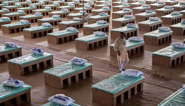 A volunteer walks past disposable beds made out of cardboard at the campus of Radha Soami Satsang Beas, a spiritual organization, where a coronavirus disease (COVID-19) care centre has been constructed for the patients amidst the spread of the disease, in New Delhi, India