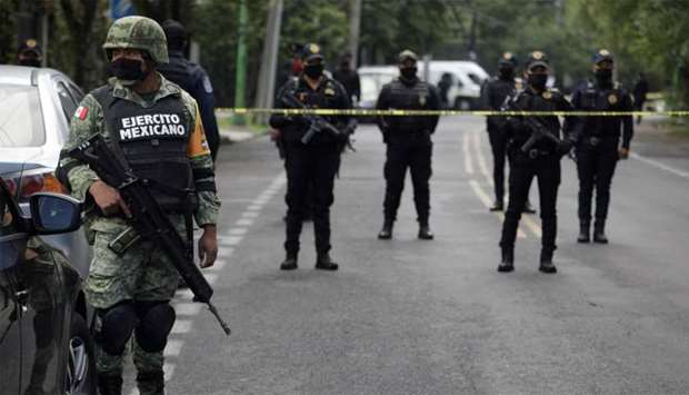 A soldier stands near police officers guarding a crime scene following an assassination attempt of Mexico City's chief of police Omar Garcia Harfuch, at the upscale neighborhood of Lomas de Chapultepec, in Mexico City