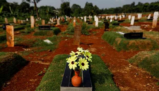 A pot of artificial flowers is placed on a grave at a burial area provided by the government for victims of the coronavirus disease at Pondok Ranggon cemetery complex in Jakarta, Indonesia