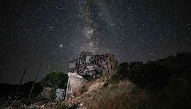 This long-exposure picture taken early yesterday shows a view of buildings destroyed by prior bombardment in the town of Ariha in Syriau2019s rebel-held northwestern Idlib province, as the Milky Way galaxy is seen in the night sky above.