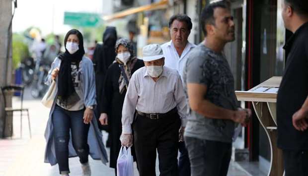 Pedestrians, some wearing protective masks due to the Covid-19 coronavirus, walk along a street in the Iranian capital Tehran, yesterday.