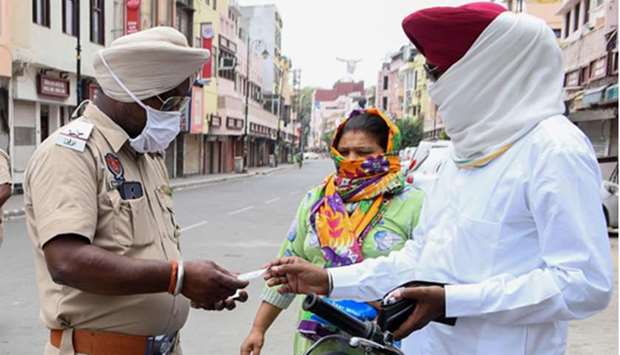 A policeman checks the travel pass from a man after strict lockdown norms for weekends and public holidays were imposed in Amritsar yesterday.