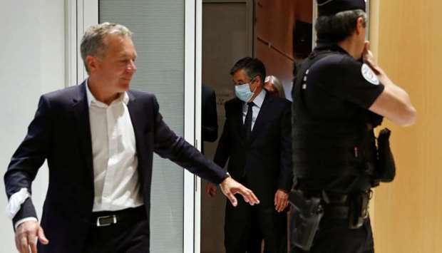 Former French prime minister Francois Fillon and his wife Penelope, wearing protective face masks, leave following the verdict in their trial over a fake jobs scandal at the courthouse in Paris