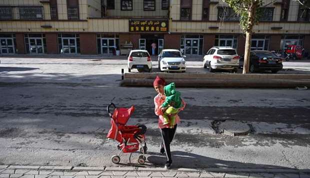 This file photo taken on September 11, 2019 shows a woman walking in an ethnic Uighur neighbourhood in Aksu in China's northwest Xinjiang region. AFP