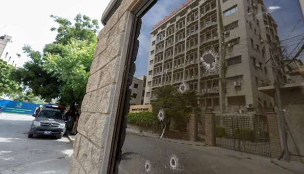 The Pakistan Stock Exchange (PSX) building in Karachi is reflected in the bullet-riddled window of the security check post following the attack.