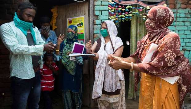 Three Accredited Social Health Activist (ASHA) workers demonstrate how to wash hands to a migrant worker during a door-to-door survey to check in Bahadarpur village in Meerut district.