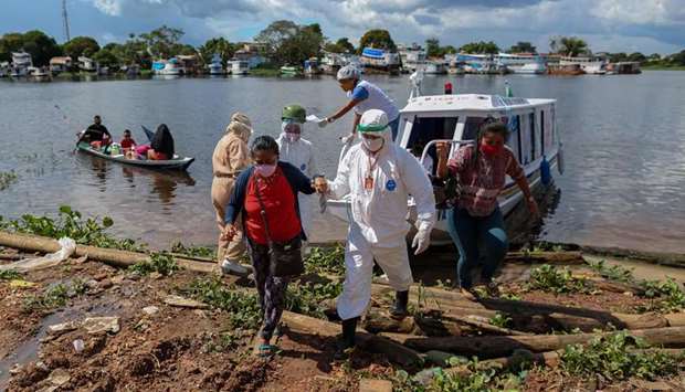 Health professionals help coronavirus patients brought on a boat ambulance from Vila Amazonia community upon their arrival in Parintins, Amazonas state, Brazil.