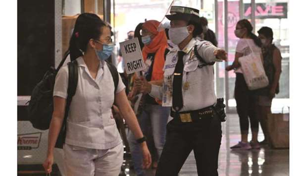 A guard guides shoppers through a walkway, as part of social distancing measures to prevent the spread of Covid-19 novel coronavirus, at a mall in Manila, yesterday.