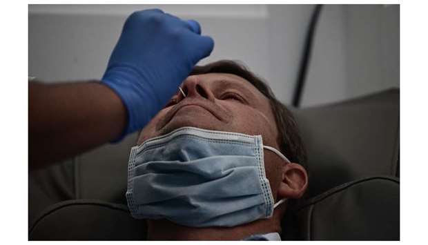 A nurse performs a nasal swab on a man at JFK International Airportu2019s Terminal 4 XpresCheck, the first airport-based Covid-19 testing facility in the US, in New York City. The pilot programme will be available to all airport employees and offers Covid and antibody testing.