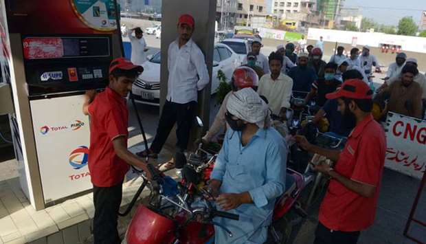 Commuters wait to fill their vehicles tanks at a gasoline station as government reduced prices of petroleum due a decrease of the global oil market, in Peshawar yesterday.