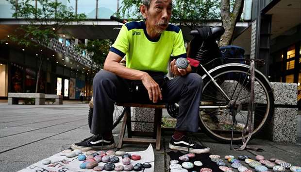 Artist Wu Rong-bi, also as know as \"Uncle Stone\", displaying colourfully painted stones along a stre