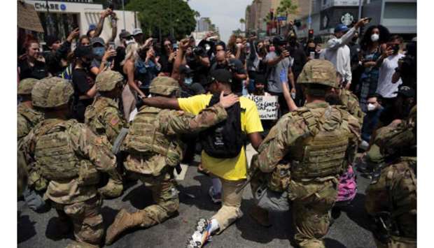 Protesters and members of the National Guard kneel together during a demonstration in Los Angeles on Tuesday.