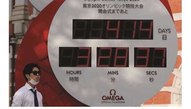 A man wearing a protective mask walks past a countdown clock for the Tokyo 2020 Olympic Games amid the coronavirus outbreak in Tokyo on Thursday. (Reuters)