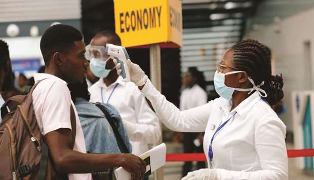 A health worker checks the temperature of a traveller as part of the coronavirus screening procedure at the Kotoka International Airport in Accra, Ghana.