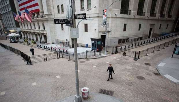 A pedestrian wearing a protective mask walks along Wall Street in front of the New York Stock Exchange. Expectations that the global economy has dodged the worst-case coronavirus pandemic scenarios have led to a dramatic sell-off in US government bonds from their record highs, pushing the yield curve to its steepest level since March.