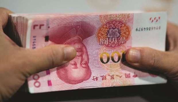 An employee counts out 100 yuan notes at a bank in Shanghai (file). Chinau2019s central bank is trying to bring down borrowing costs across the economy to stimulate demand and help China grow out of the slump in the first quarter caused by the pandemic.