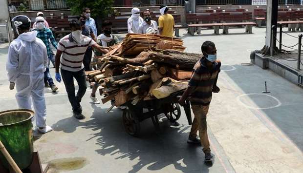 Workers pull a cart loaded with cremation wood at the Nigambodh Ghat cremation ground in New Delhi on June 3.