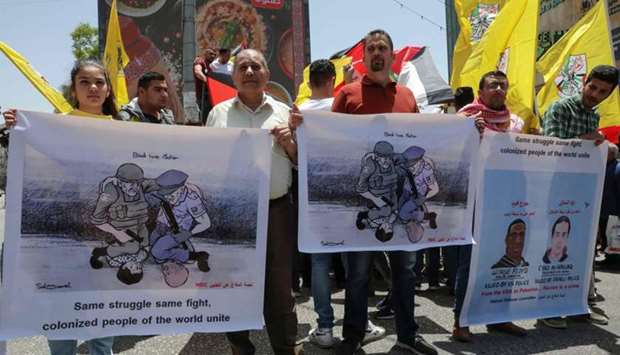 Palestinians lift banners protesting the killing of Iyad Hallak, a disabled Palestinian man shot dead by Israeli police, and that of George Floyd, an unarmed black man who died after a white policeman knelt on his neck during an arrest in the US, during a rally by supporters of the Fatah movement in the West Bank city of Hebron