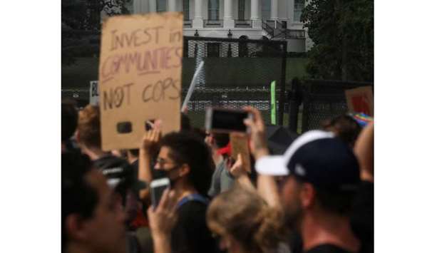 Demonstrators stand behind a fence at Lafayette Park in front of the White House during a protest against racial inequality.