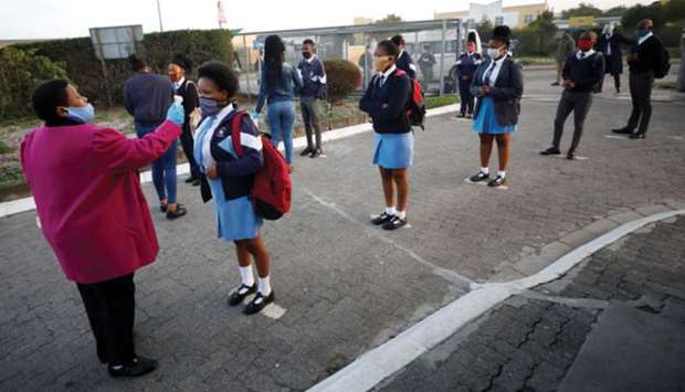 A teacher screens students as schools reopened yesterday in Langa township in Cape Town.