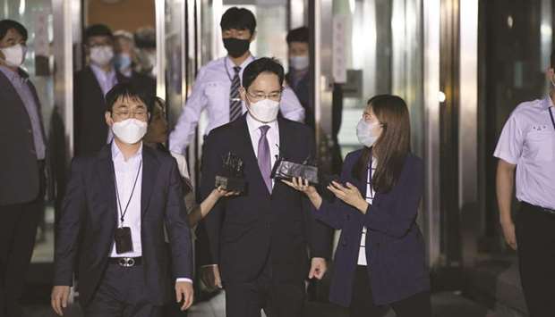 Jay Y Lee, co-vice chairman of Samsung Electronics Co (centre), wears a protective mask as he is surrounded by members of the media while leaving at the Seoul Central District Court yesterday.