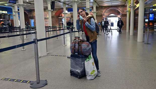 A passengers puts on a face mask as a precautionary measure against Covid-19, after arriving at St Pancras International station in central London, yesterday as the governmentu2019s planned 14-day quarantine for international arrivals to limit the spread of the novel coronavirus begins.