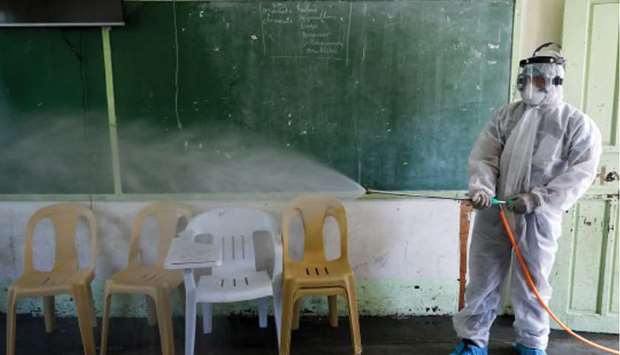 File photo shows a worker disinfecting a classroom inside a high school amid new cases of coronavirus in the country, in San Juan, Metro Manila.