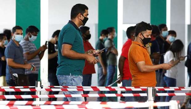 Essential workers queue up to have their noses swabbed before returning to the workforce at a regional screening center amid the coronavirus disease outbreak in Singapore